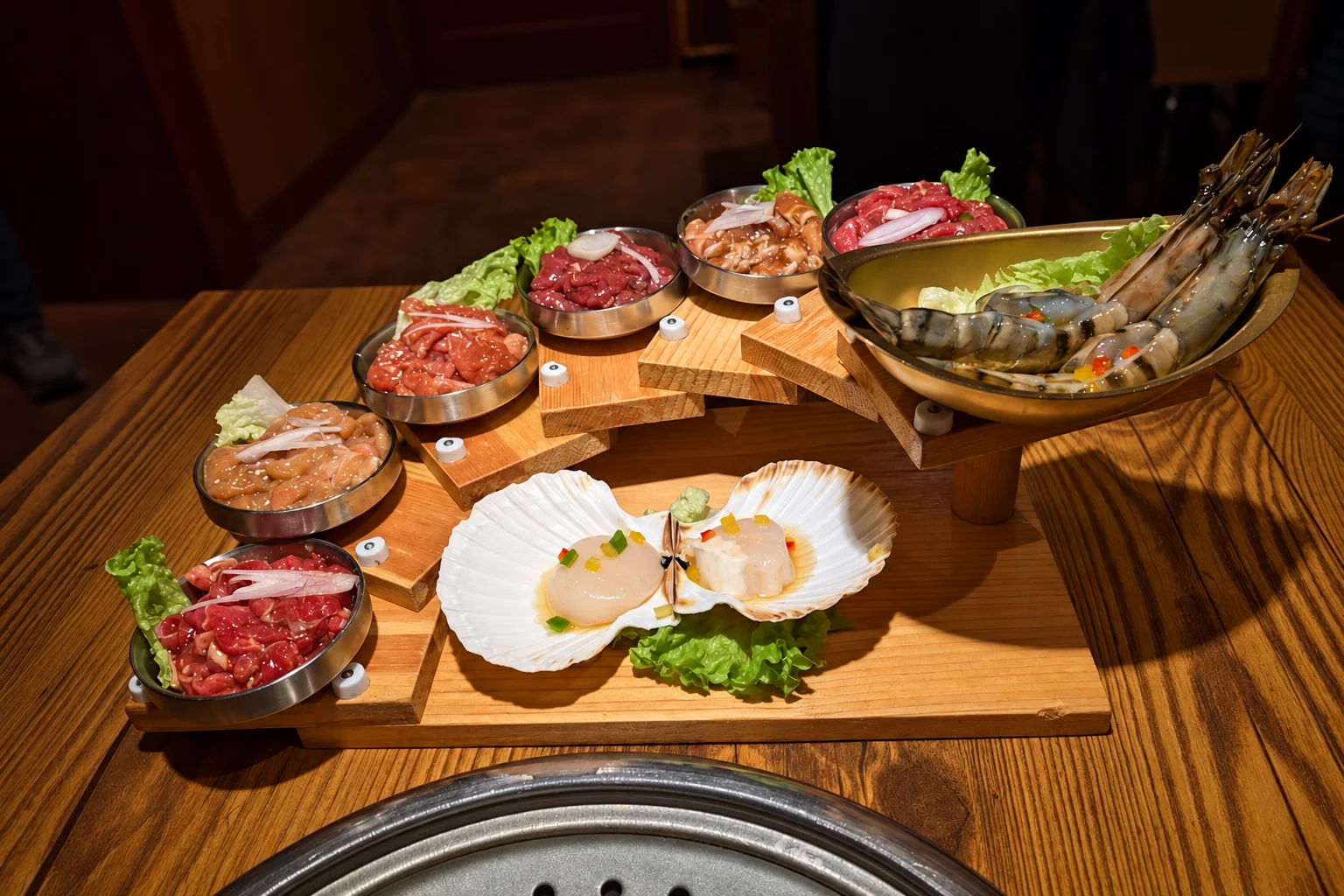 Meat and seafood for the grill on a wooden restaurant table, in front of the table grill